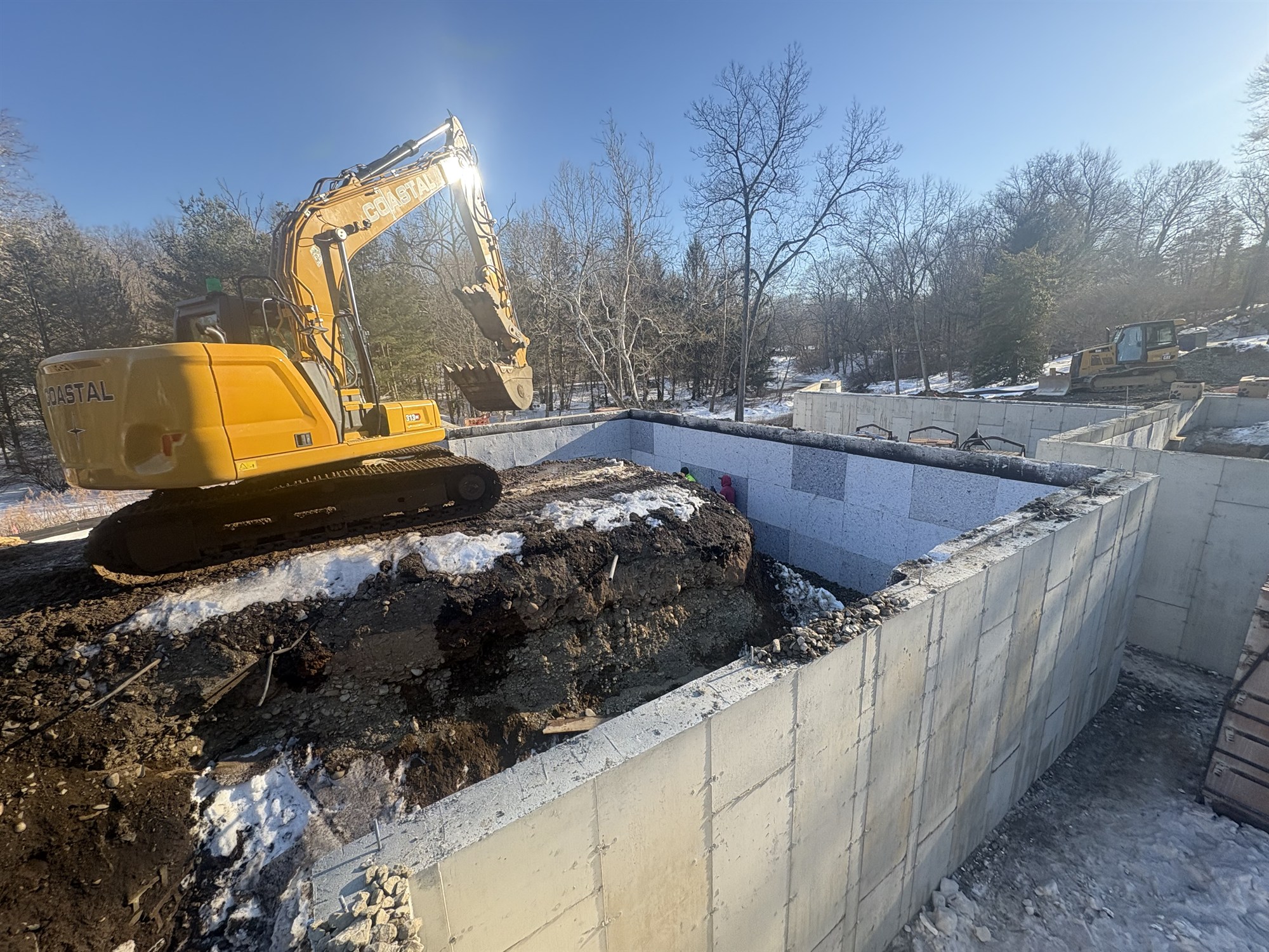 A CLH CAT excavator backfilling a new foundation on a Connecticut home site